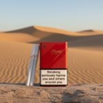 ซองบุหรี่ Davidoff Supreme สีแดง วางบนขอนไม้ท่ามกลางทะเลทรายสีทอง สไตล์หรูหราพรีเมียม