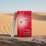 ซองบุหรี่ ESSE Change Strawberry สีแดงชมพูสดใส วางบนขอนไม้ในฉากหลังทะเลทรายสีทอง