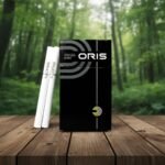 ซองบุหรี่ Oris Intense Black วางบนโต๊ะไม้ในบรรยากาศป่าเขียวขจี แสดงดีไซน์หรูหราสีดำสลับเงิน