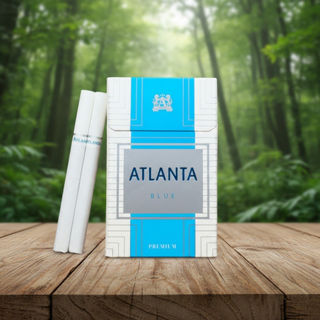 ซองบุหรี่ Atlanta Blue Premium สีขาวฟ้าและมวนบุหรี่สีขาวสะอาดตา วางบนโต๊ะไม้ในบรรยากาศป่า
