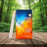 ซองบุหรี่ ESSE Change Double Orange สีส้มฟ้าสดใส พร้อมมวนบุหรี่มวนเรียวเล็กวางบนโต๊ะไม้ท่ามกลางพื้นหลังป่าไม้