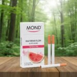 บุหรี่ Mond Watermelon ซองสีขาวรูปแตงโม วางคู่กับมวนบุหรี่ซุปเปอร์สลิมบนโต๊ะไม้ ฉากหลังป่าไม้สีเขียว