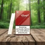 บุหรี่ Davidoff Classic ซองสีแดงเข้มดีไซน์หรูหราวางคู่กับมวนบุหรี่บนโต๊ะไม้ ฉากหลังป่าไม้สีเขียว