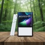 บุหรี่ Mevius Option 2 No.5 ซองสีดำลายสีม่วงเขียว วางคู่กับมวนบุหรี่ที่มีเม็ดบีบ 2 จุดบนโต๊ะไม้ ฉากหลังป่า