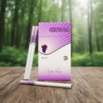 กล่องบุหรี่ Oris Grape สีม่วงขาวดีไซน์ทันสมัย วางบนโต๊ะไม้ฉากหลังป่าไม้สีเขียว